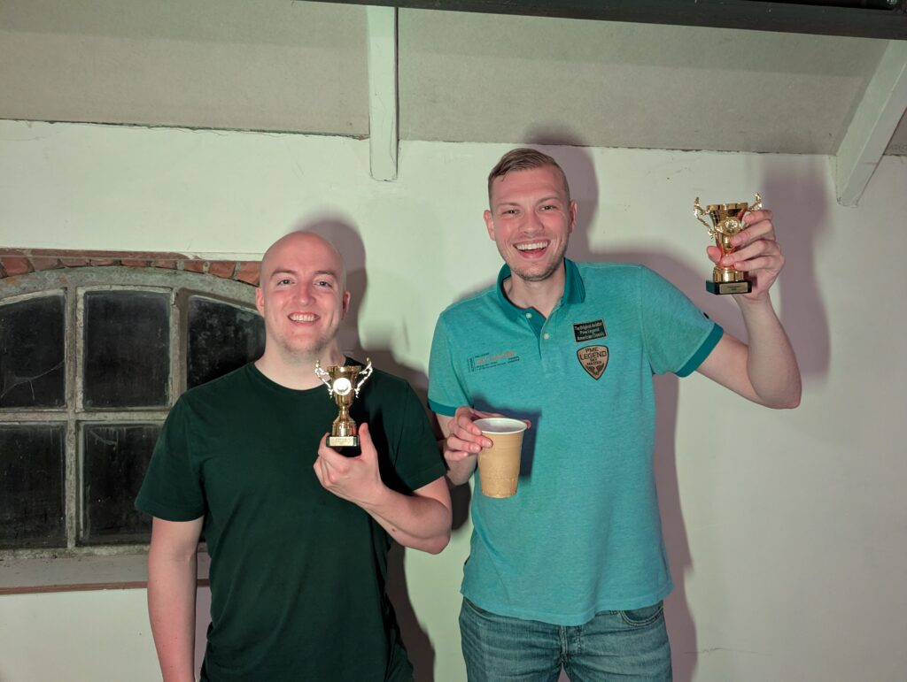 Twee winnaars poseren met trofeeën tijdens Loef-LAN LAN-party, glimlachend voor de camera in een gezellige setting.